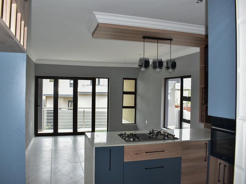 Modern open-plan kitchen featuring a central island with a built-in gas hob, sleek cabinetry, and seamless flow to the adjacent living area.