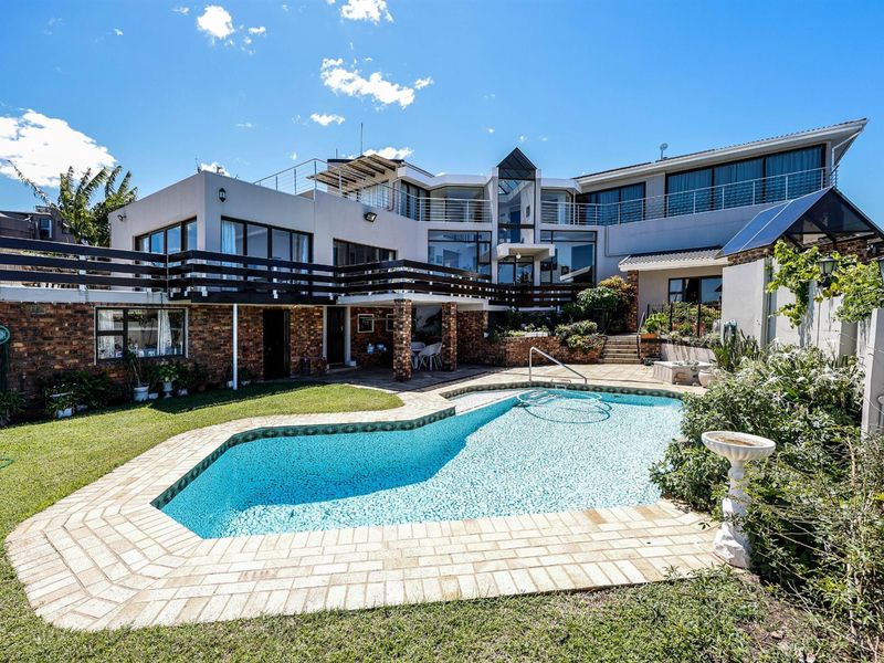 Spacious rear exterior featuring a large swimming pool, paved surround, multi-level balconies, and established garden areas.