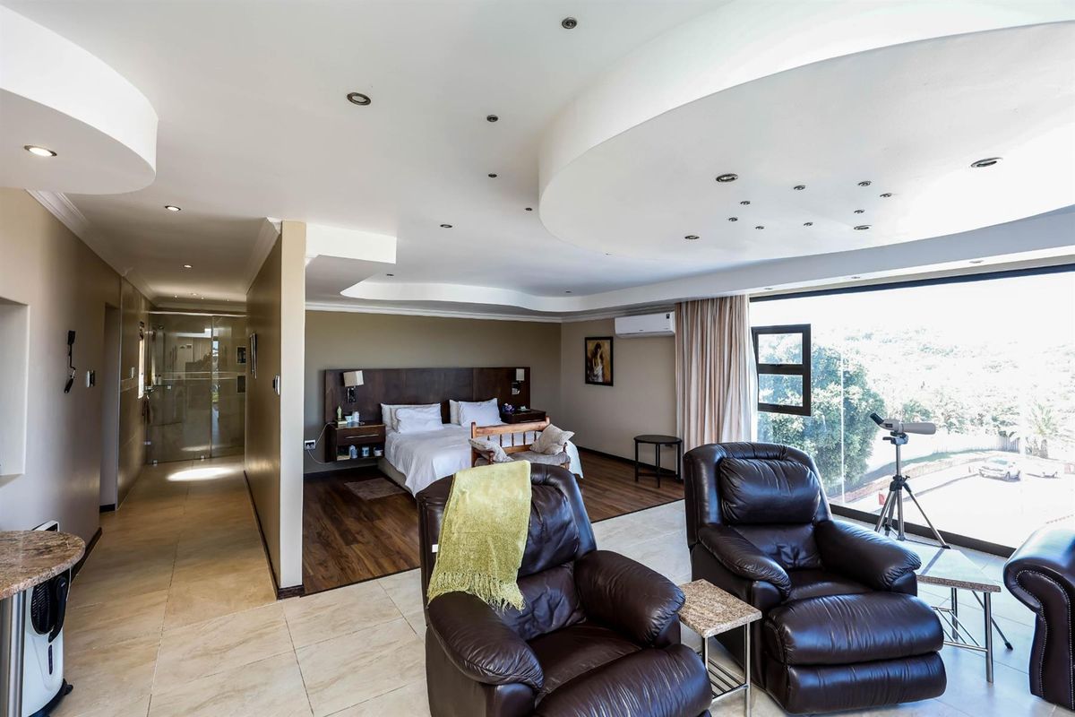 Spacious open-plan bedroom suite featuring a modern recessed ceiling with integrated downlights, large windows, and an en-suite bathroom area with glass partitioning.