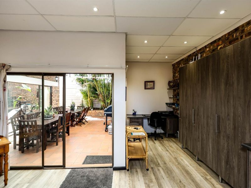 A functional office space featuring built-in cabinetry and wood-look flooring, with direct access to an outdoor patio area through sliding glass doors.