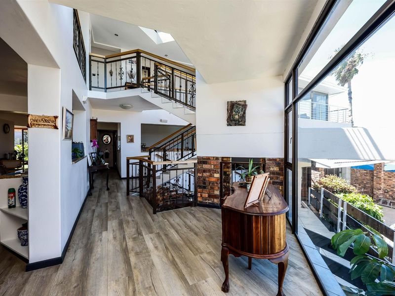 Spacious multi-level entrance hall featuring a grand staircase with wrought iron balustrades, large windows, and wood-look flooring.