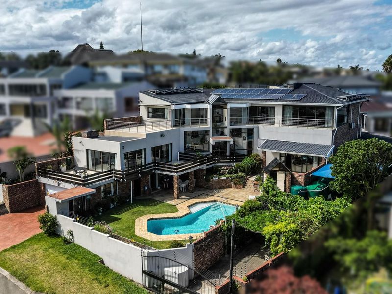 Aerial view of a multi-level residential property featuring a swimming pool, landscaped garden, multiple balconies, and rooftop solar panels.