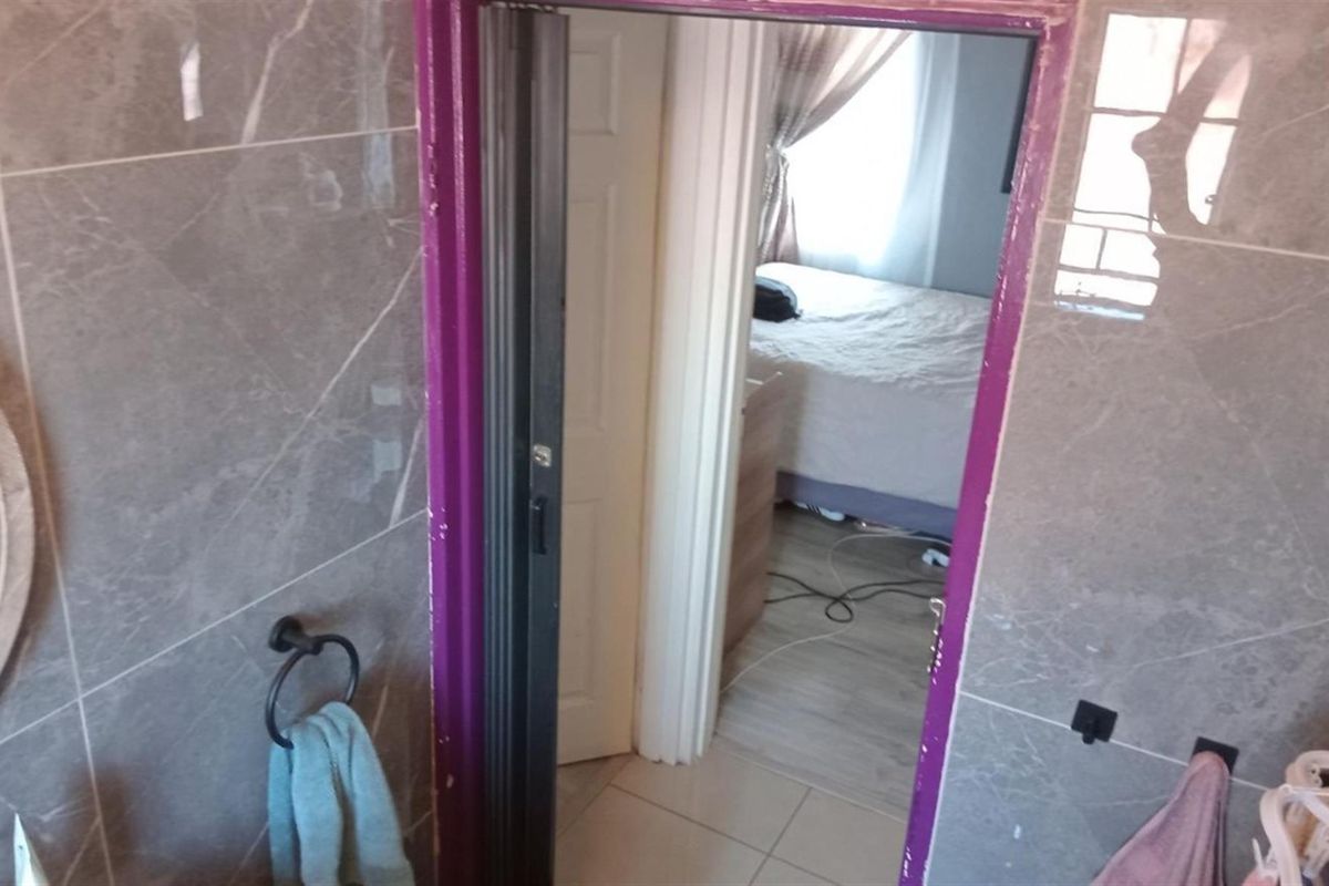 A view from a tiled bathroom looking through a doorway into an adjacent bedroom.