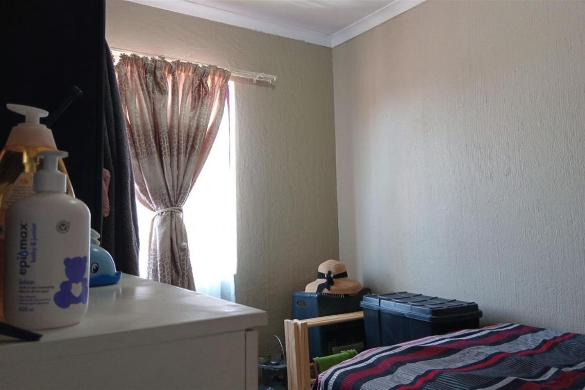 A bedroom featuring textured walls, a window with curtains, and crown molding.