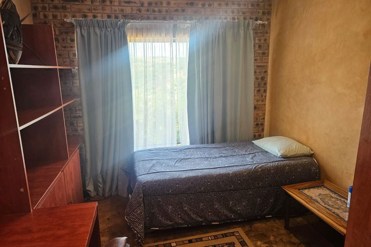 A bedroom featuring exposed brick walls, a window with curtains, and built-in shelving units.