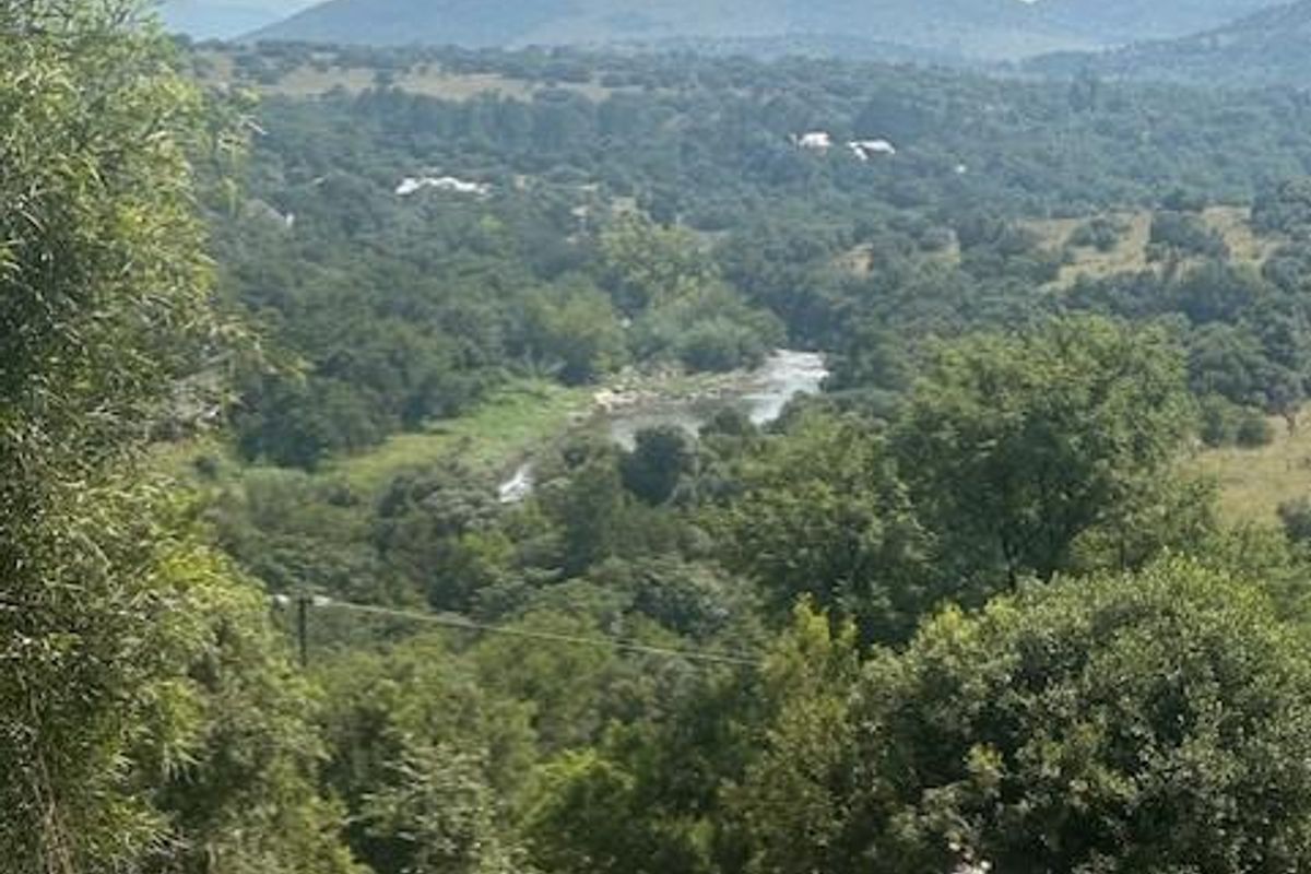 A scenic view overlooking a lush valley with a winding river and prominent mountain peaks in the distance.
