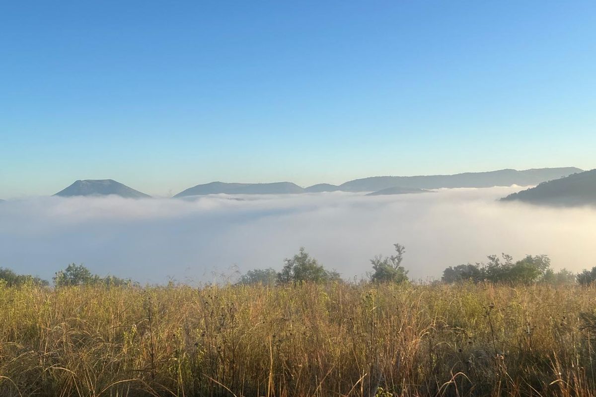 A scenic view of rolling hills and mountains partially obscured by morning mist, captured from the vacant residential land.