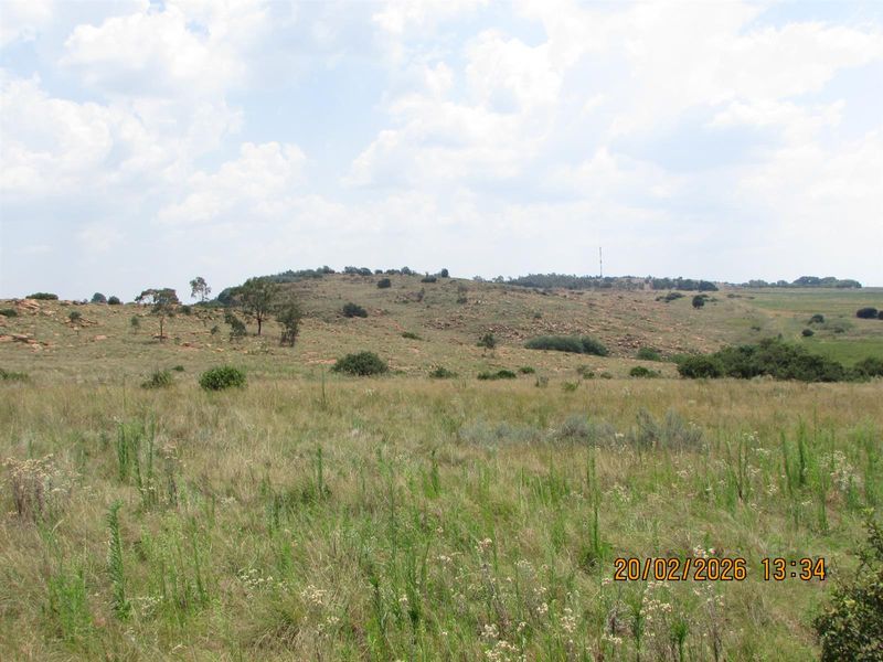 A wide-angle view of the expansive natural grassland and rocky terrain characteristic of the farm property.
