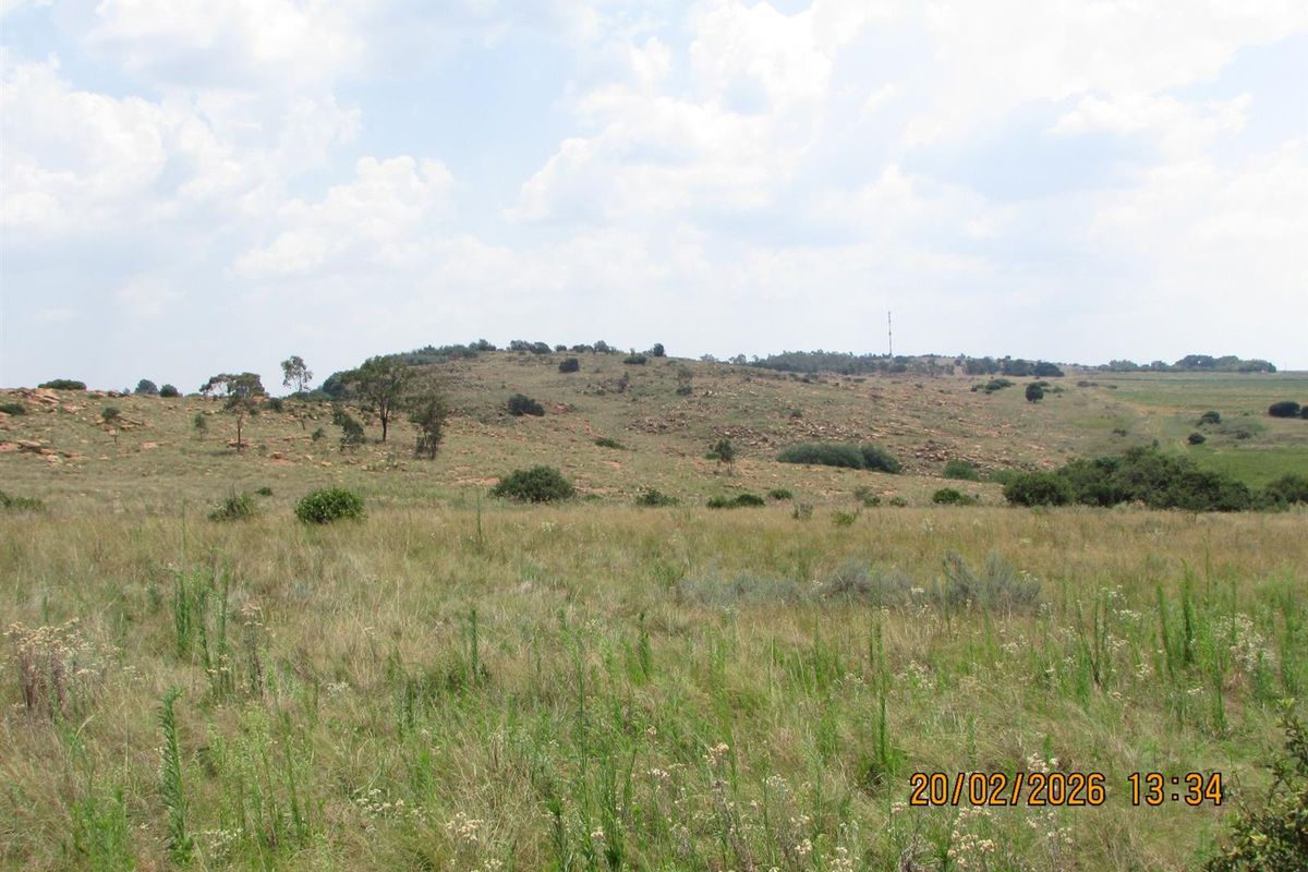 A wide-angle view of the expansive natural grassland and rocky terrain characteristic of the farm property.