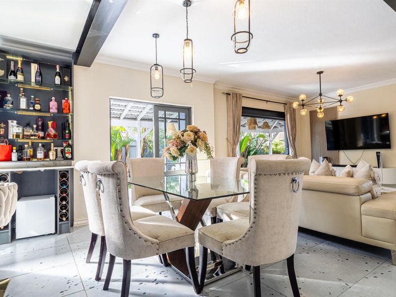 Spacious open-plan living and dining area featuring modern terrazzo-style flooring, built-in bar cabinetry, and seamless access to the outdoor patio through sliding glass doors.