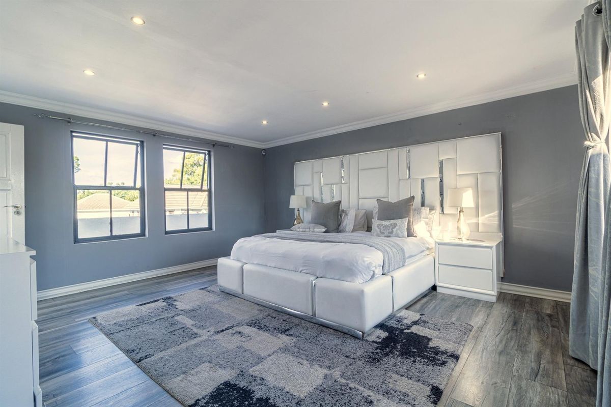 Spacious bedroom featuring modern laminate flooring, recessed downlighting, and large windows that provide ample natural light.