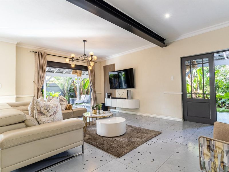 Spacious living room featuring modern terrazzo-style flooring, an exposed steel beam, and direct access to the outdoor patio area.