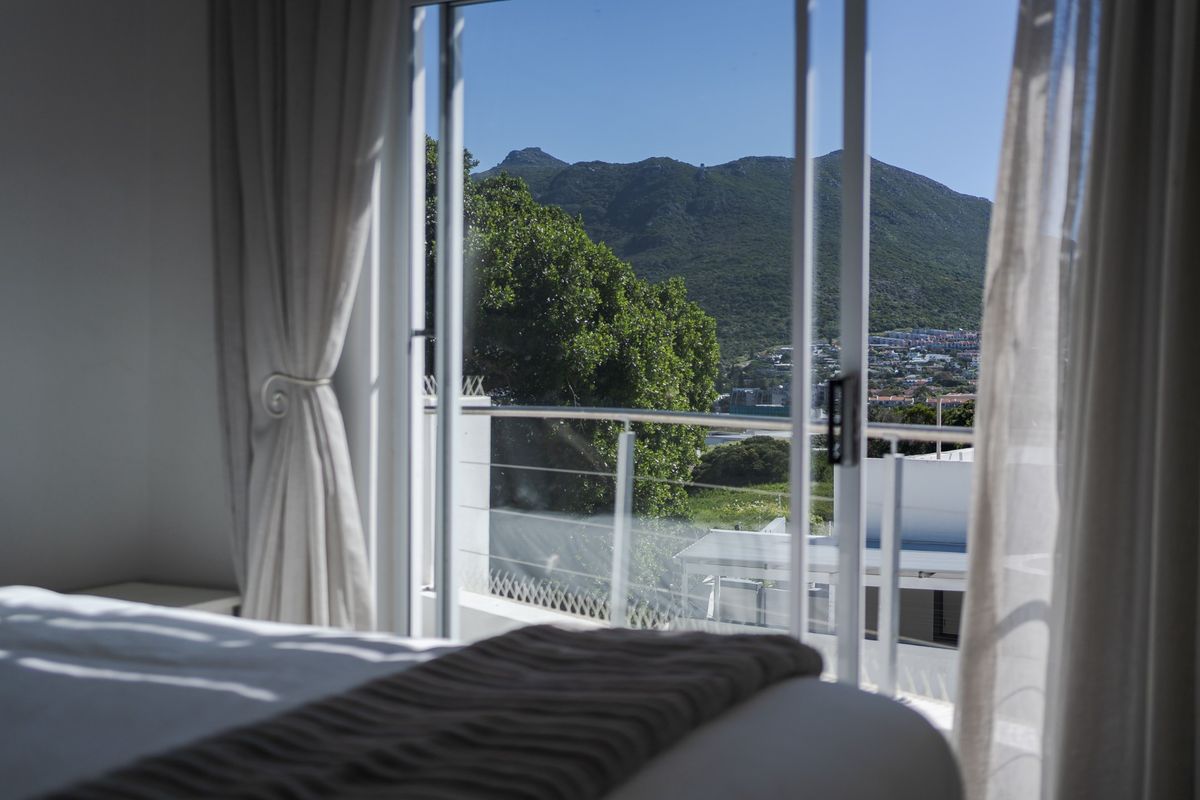 A bedroom featuring a sliding glass door that opens onto a balcony with scenic mountain and neighborhood views.