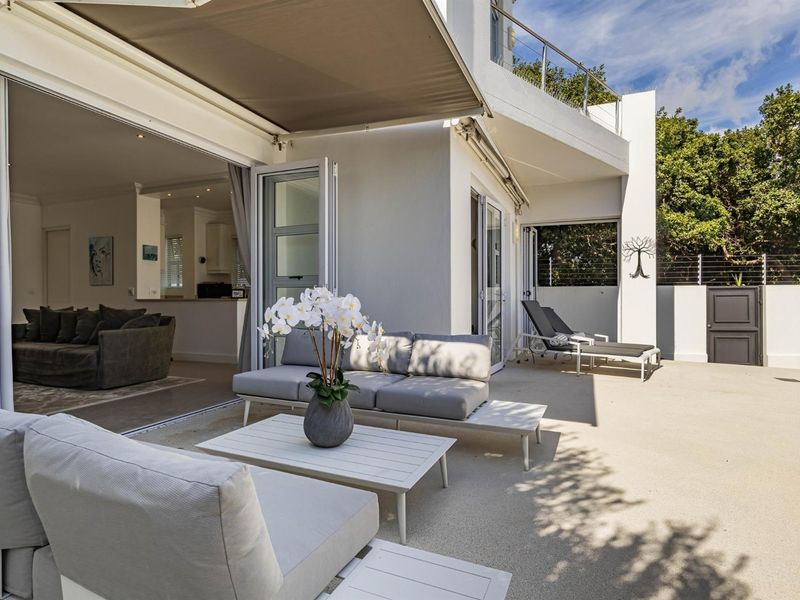 Spacious outdoor patio featuring a retractable awning, seamless indoor-outdoor flow through stacking doors, and a well-maintained paved entertainment area.