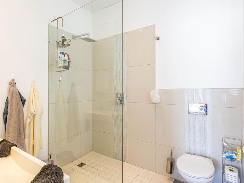 Modern bathroom featuring a walk-in shower with glass screen, wall-mounted toilet, and elegant mosaic tile accents.