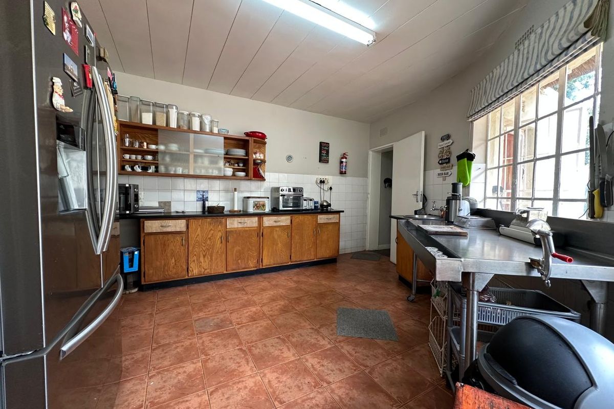 A functional kitchen featuring wooden cabinetry, tiled flooring, and a stainless steel prep area, offering a practical layout for farm-style living.