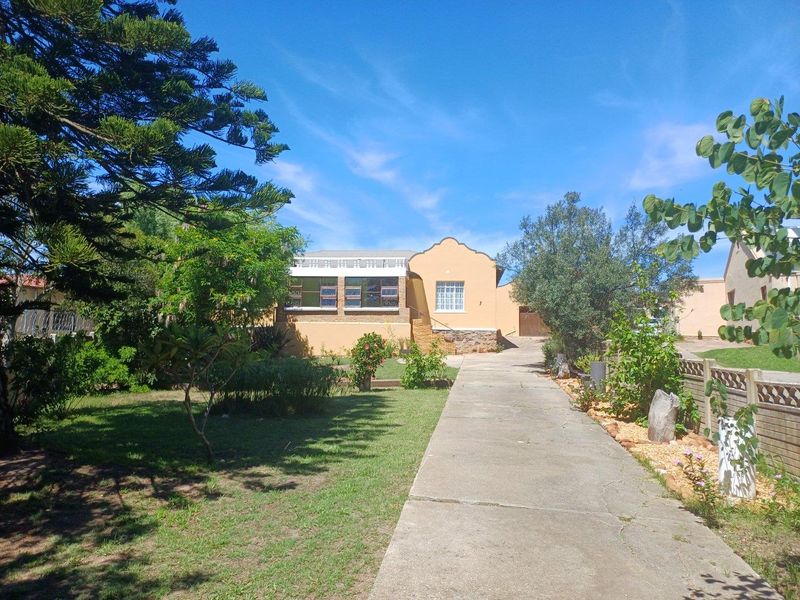 A view of the front exterior of the house, featuring a concrete driveway, landscaped garden, and traditional architectural facade.
