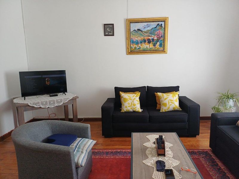 A comfortable living room featuring warm timber flooring and neutral wall finishes, providing a functional and inviting space for relaxation.