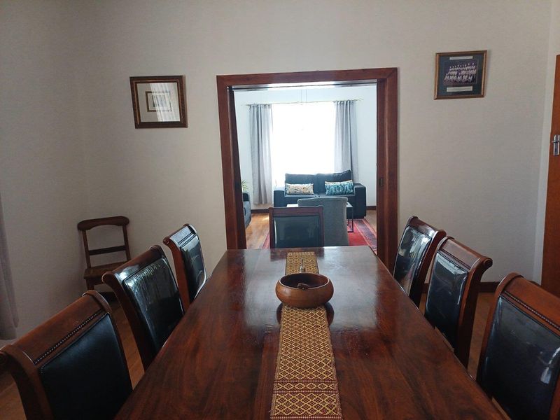 A formal dining room featuring wooden flooring and a large doorway leading into an adjacent living area.
