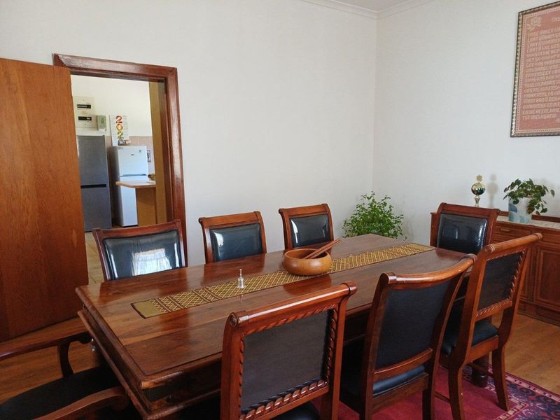 A formal dining room featuring wooden flooring and a doorway leading into the kitchen area.