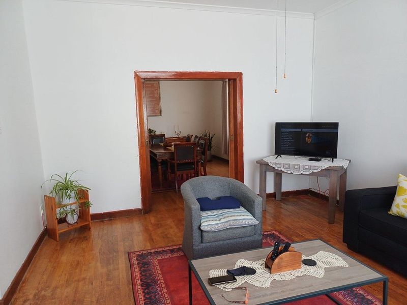 A living room featuring original timber flooring and a wide doorway leading into an adjacent dining area.
