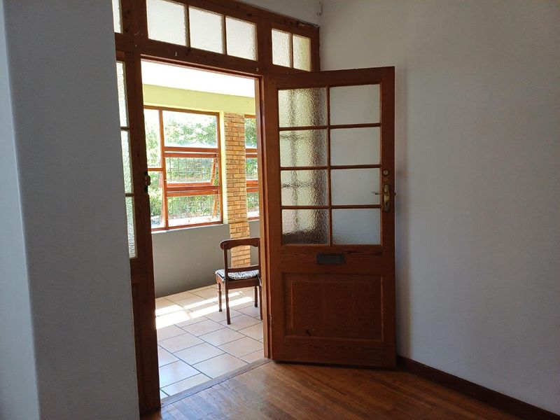 Interior view looking through a traditional timber-framed glass door onto a covered patio area with tiled flooring.