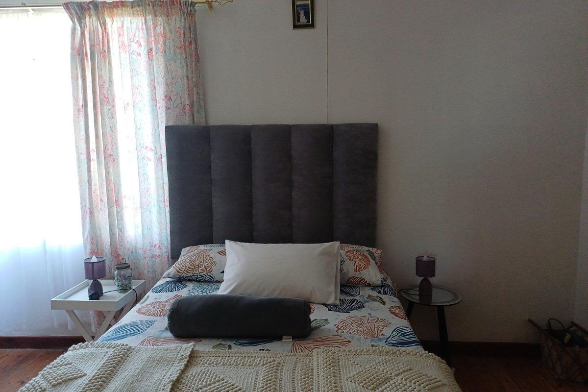 A bedroom featuring timber flooring and a window with natural light.