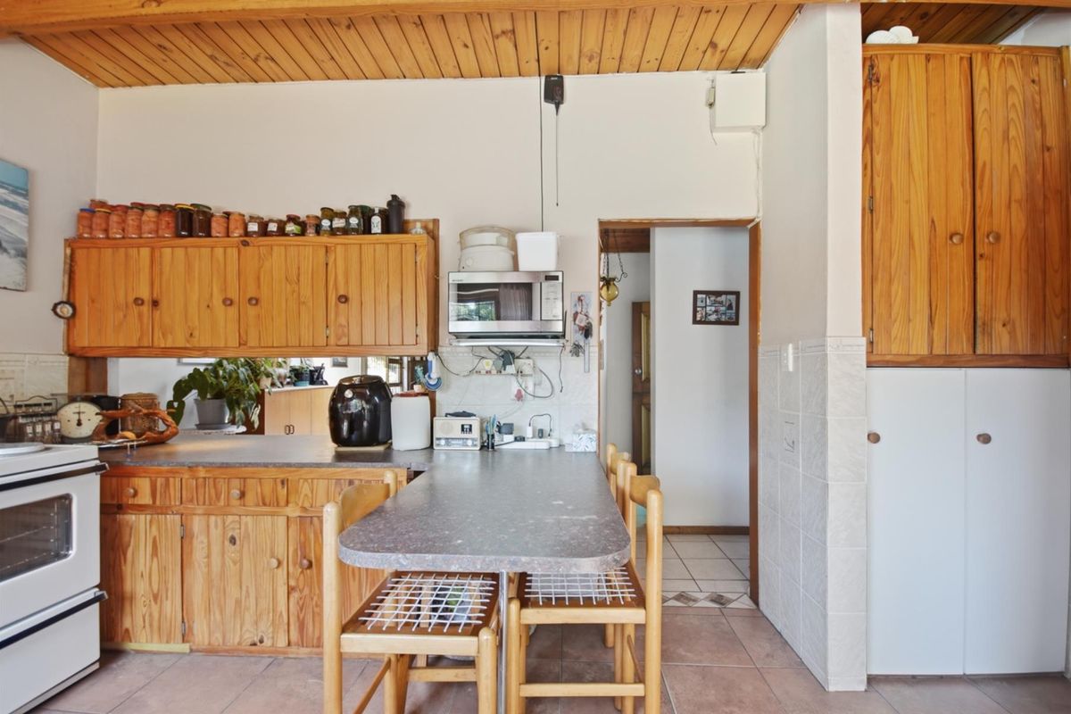A functional kitchen featuring timber cabinetry, laminate countertops, a tiled splashback, and a timber-clad ceiling, offering a traditional aesthetic with potential for modernization.
