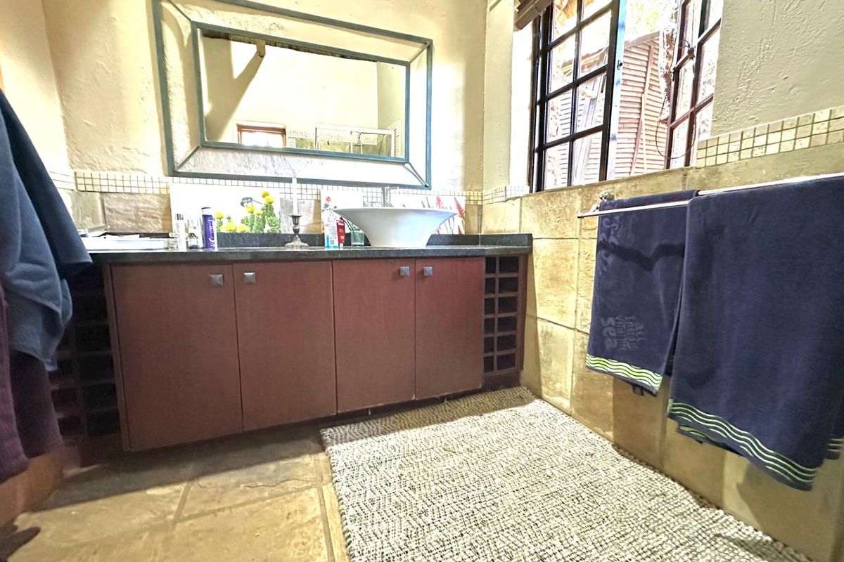 A bathroom featuring a vessel sink, granite vanity countertop, built-in wooden cabinetry, and tiled finishes with a framed mirror.