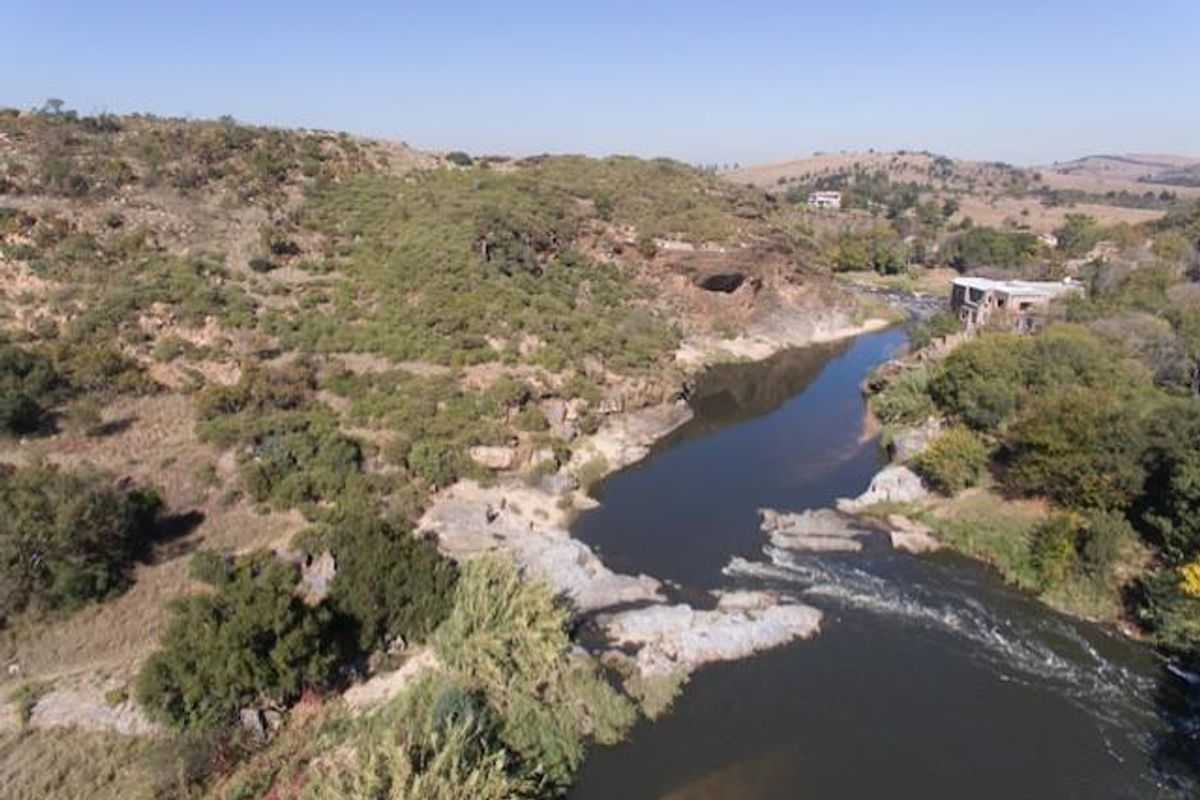 An aerial view of the property showcasing the natural river landscape and surrounding rocky terrain.