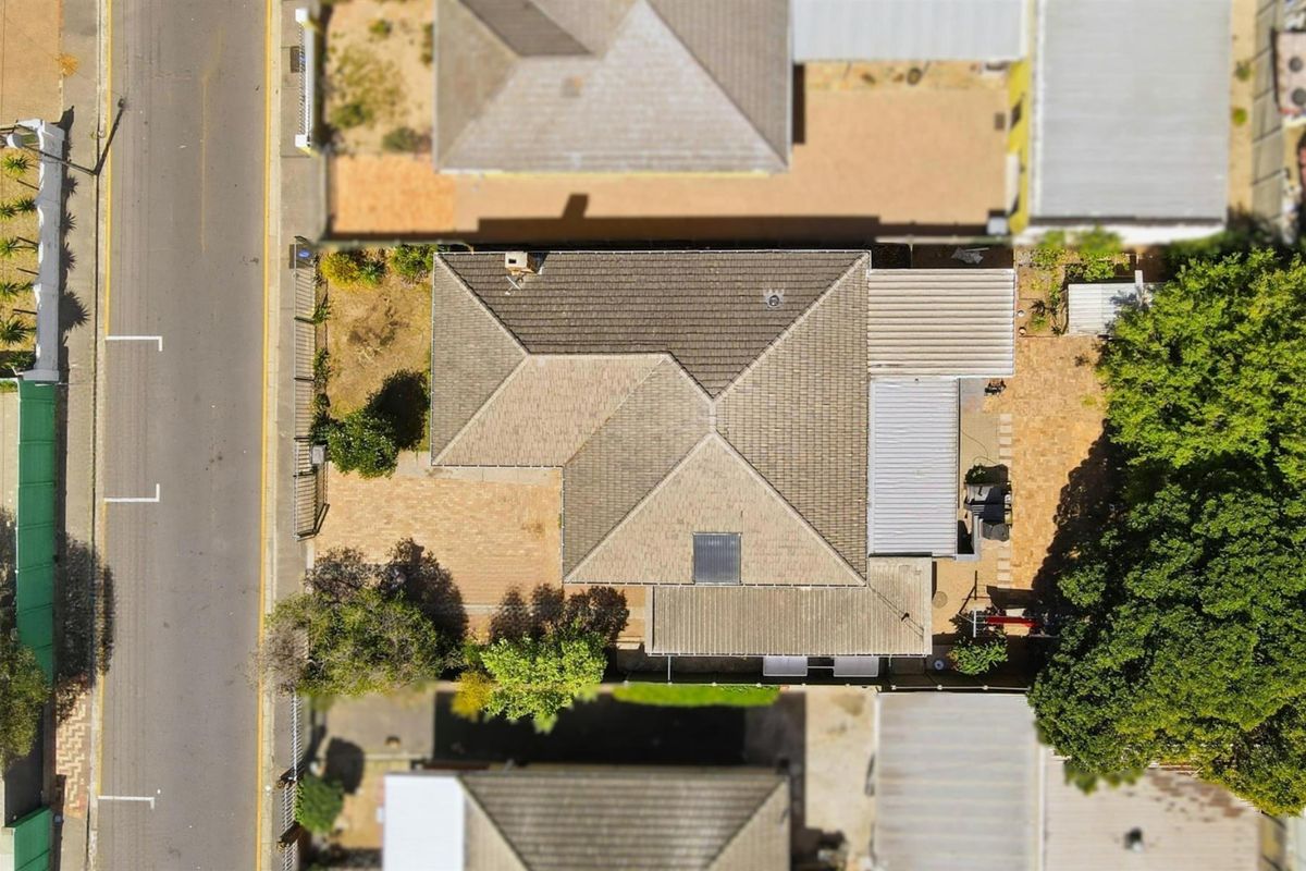 An aerial view of the property showing the roof structure, paved driveway, and surrounding garden area.
