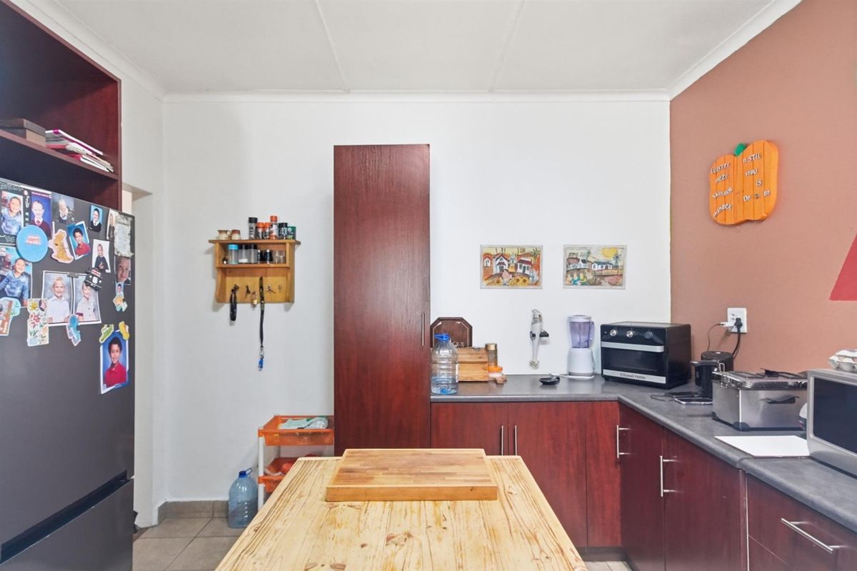 A functional kitchen featuring dark wood cabinetry, laminate countertops, and tiled flooring, providing a practical workspace for daily meal preparation.