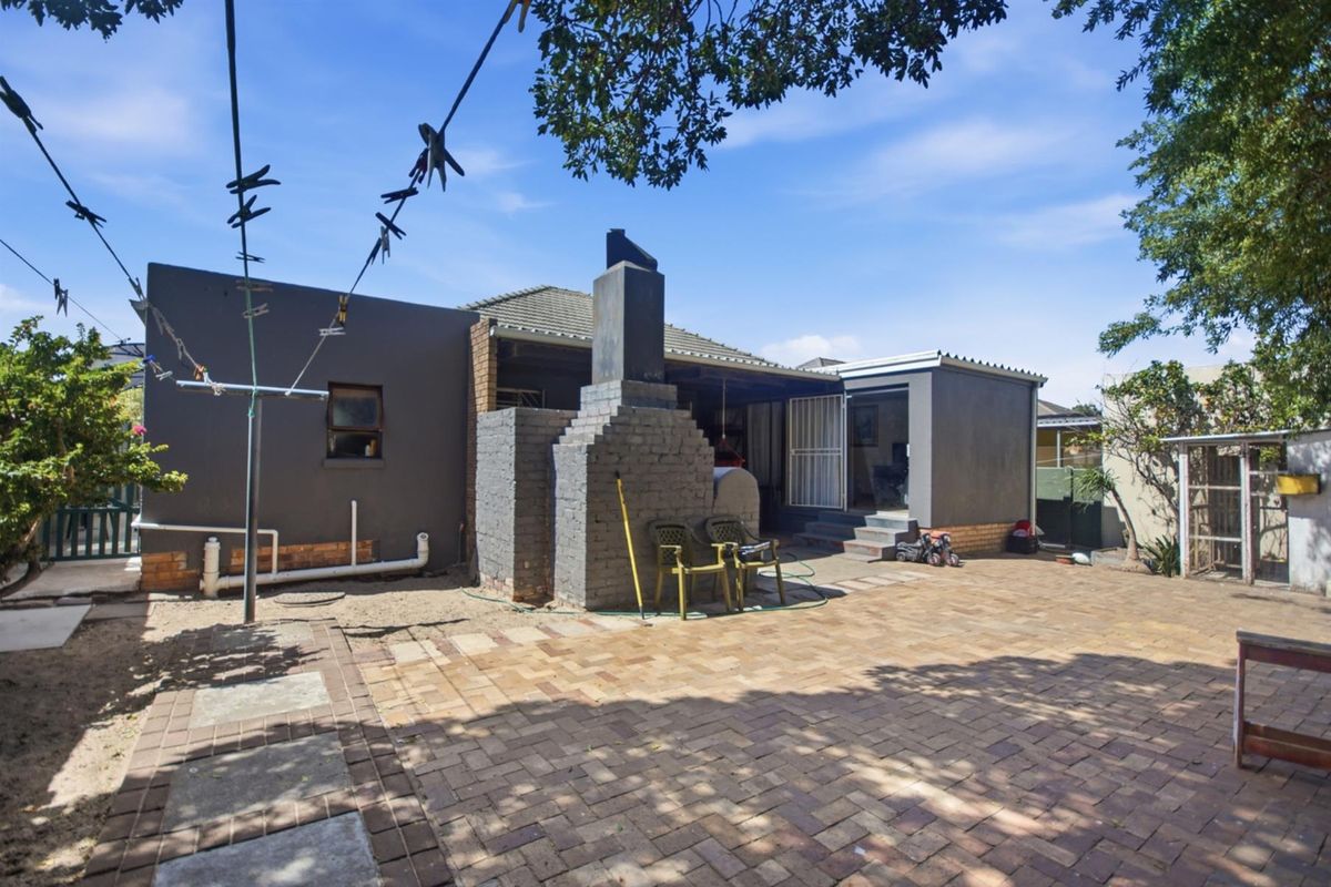 Rear exterior view featuring a paved patio area, a built-in brick braai, and direct access to the home.