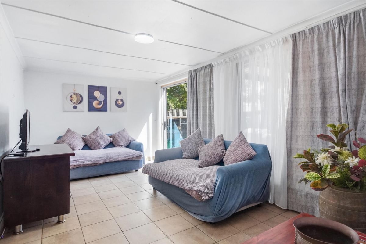 A bright living room featuring tiled flooring, large sliding glass doors providing natural light, and direct access to the outdoor area.