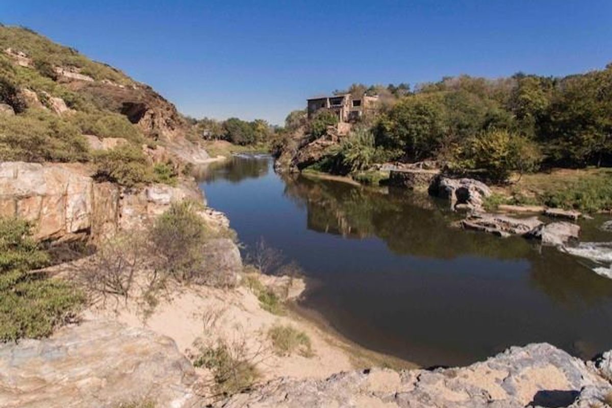A scenic landscape view featuring a river flowing through a rocky terrain with the property visible in the distance.