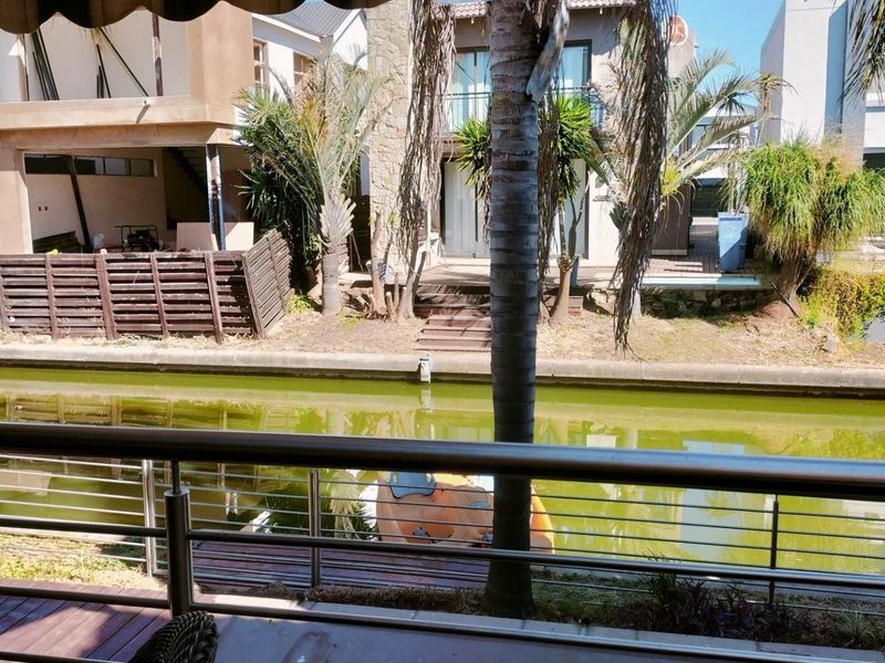 View of a canal-front property featuring a timber deck, stainless steel balustrade, and direct water access.