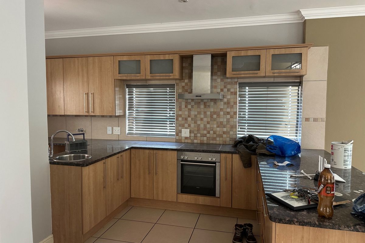A functional kitchen featuring light wood cabinetry, granite countertops, a mosaic tile backsplash, and integrated stainless steel appliances.