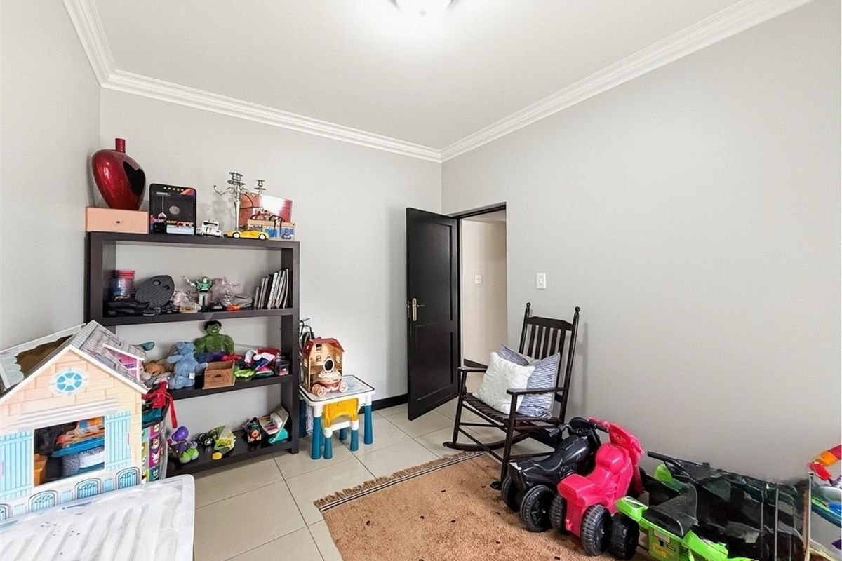 A well-maintained bedroom featuring neutral wall tones, tiled flooring, and decorative cove cornicing, providing a versatile space for various uses.