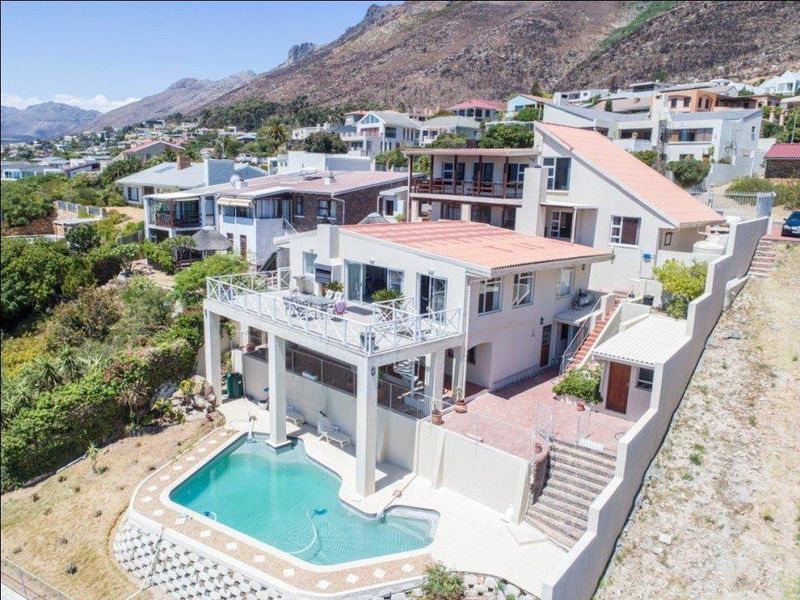 Aerial view of a multi-level residential property featuring a swimming pool, expansive paved patio areas, and tiered outdoor spaces with mountain views.