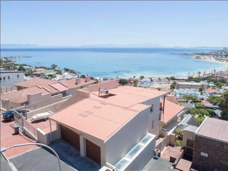 Elevated aerial view of the property showcasing its coastal location, tiled roof, and double garage with proximity to the beach.