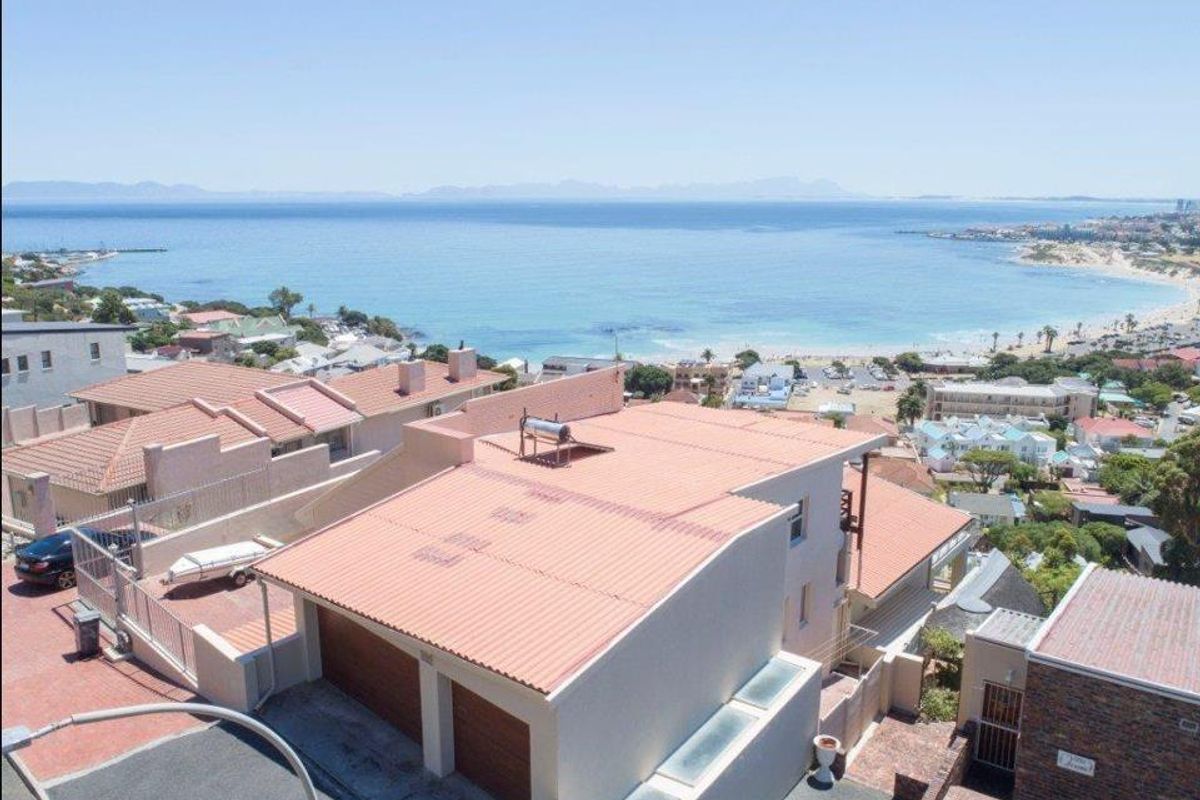Elevated aerial view of the property showcasing its coastal location, tiled roof, and double garage with proximity to the beach.
