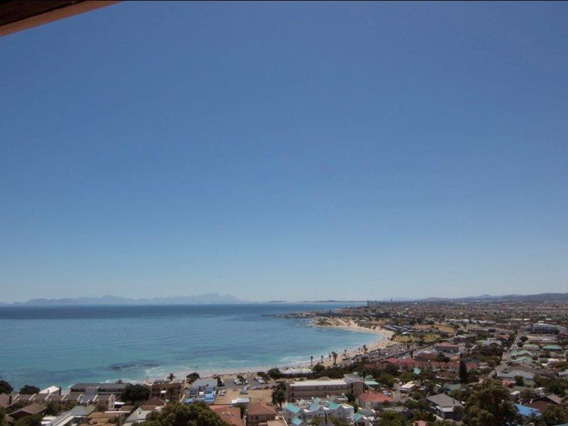 A panoramic elevated view overlooking the coastline, beach, and surrounding residential neighborhood under a clear blue sky.