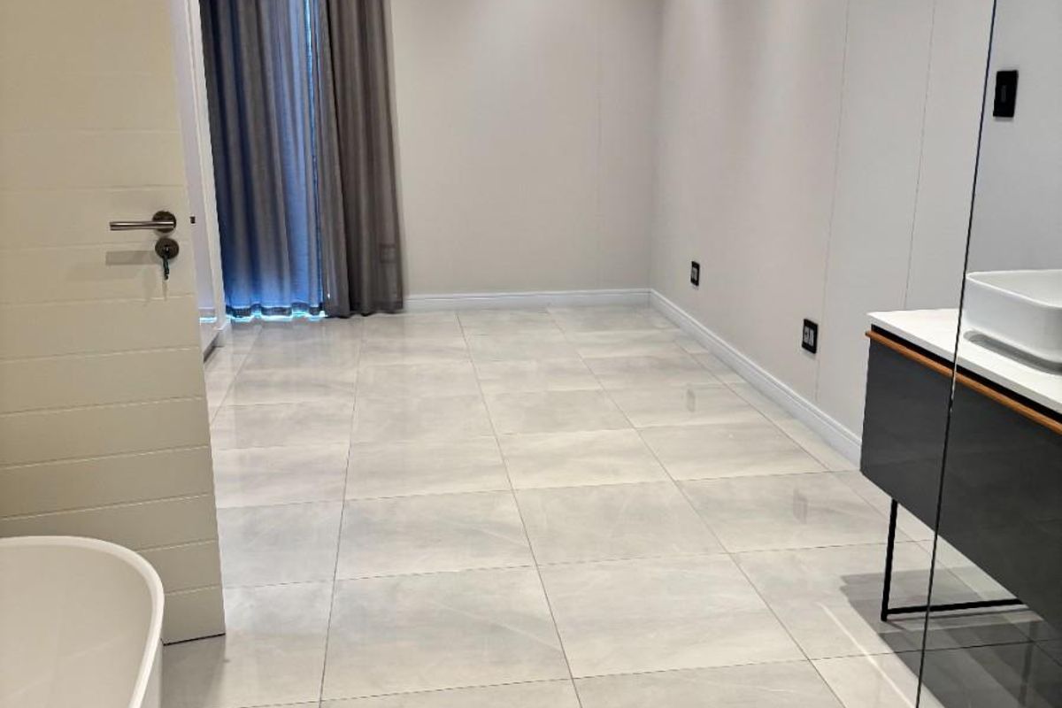 Modern bathroom featuring large format floor tiles, a floating vanity with a vessel sink, and a freestanding bathtub.