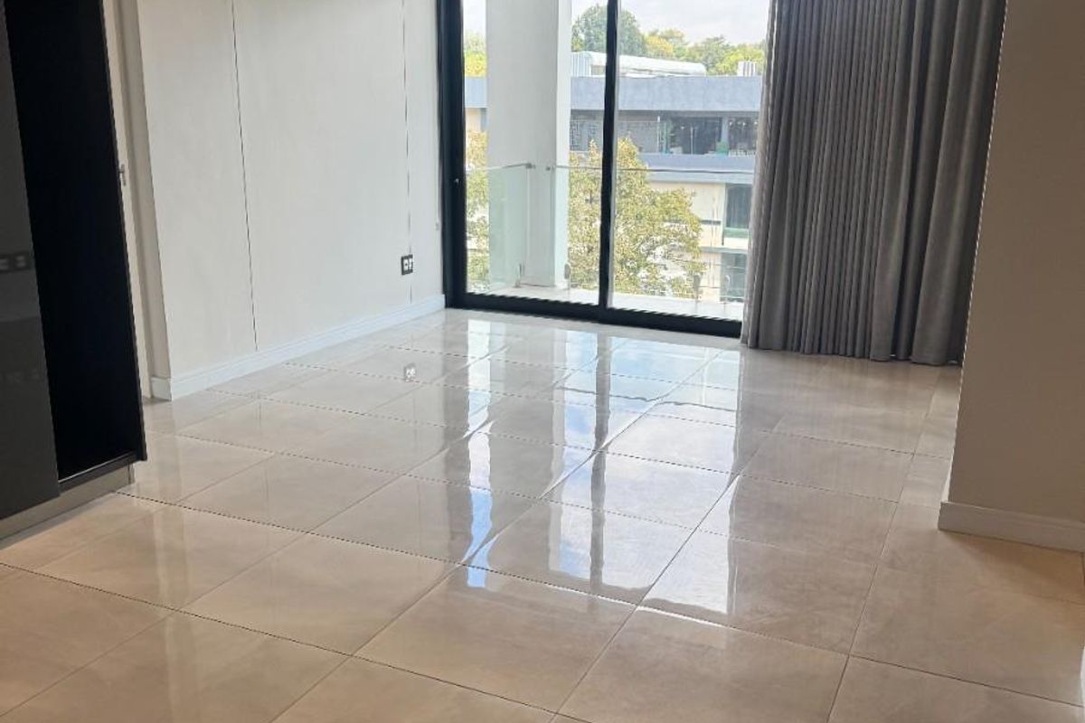 A bright, modern bedroom featuring polished porcelain floor tiles, recessed ceiling lighting, built-in cabinetry, and large sliding glass doors leading to a private balcony.