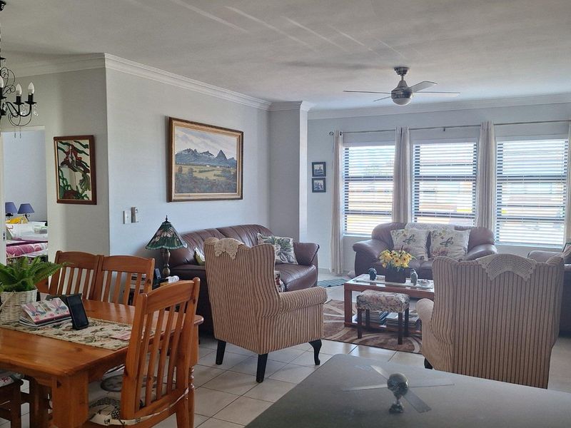 Open plan living and dining area featuring tiled flooring, ceiling fan, and large windows with blinds, providing a bright and functional living space.