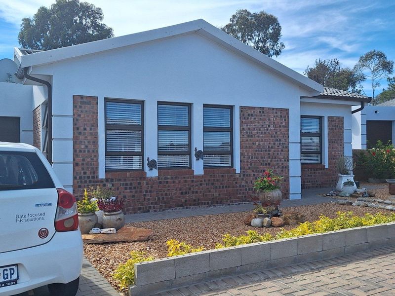 Front facade of a modern house featuring a combination of face brick and white plaster finishes with aluminium window frames.