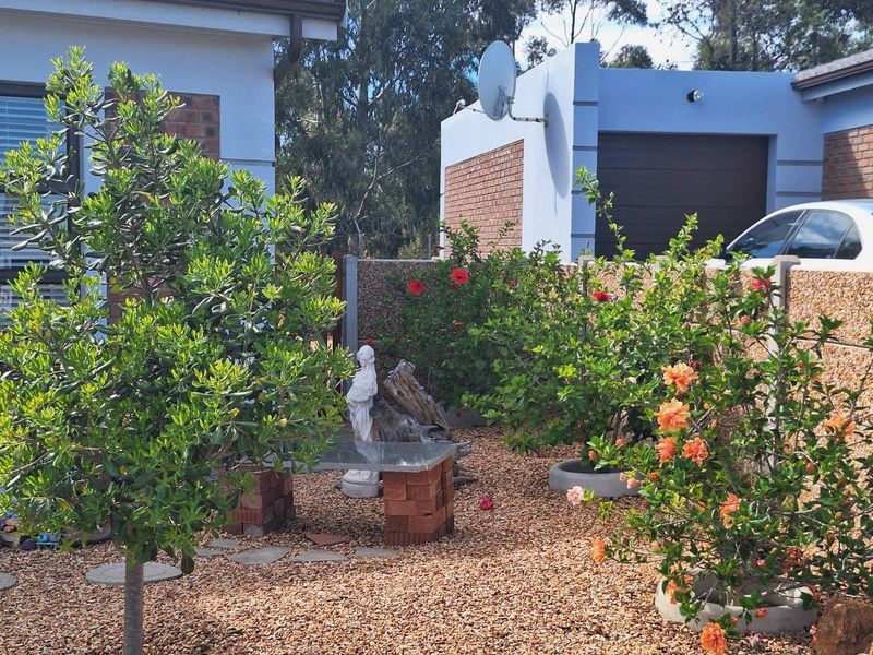 A low-maintenance garden area featuring gravel landscaping, established shrubs, and a brick-based stone bench, situated between residential building structures.