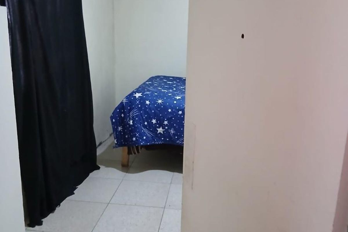 A compact bedroom featuring tiled flooring and a ventilation grille, requiring cosmetic updates to improve its overall condition and appeal.