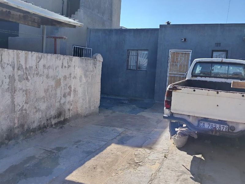 Rear exterior view of the property featuring a concrete driveway, boundary wall, and security-fitted access points.