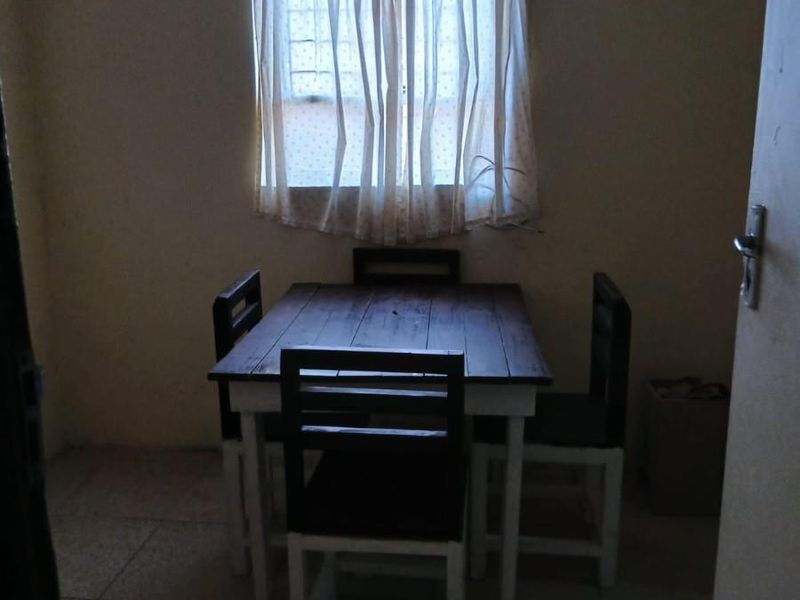 A compact dining area featuring tiled flooring and a window with natural light, providing a functional space for meals.